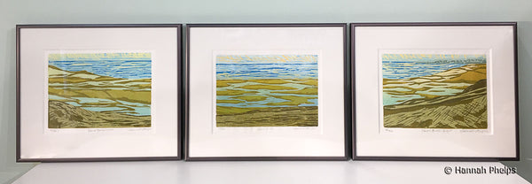 Three framed woodblock prints of a New England beach by artist Hannah Phelps.