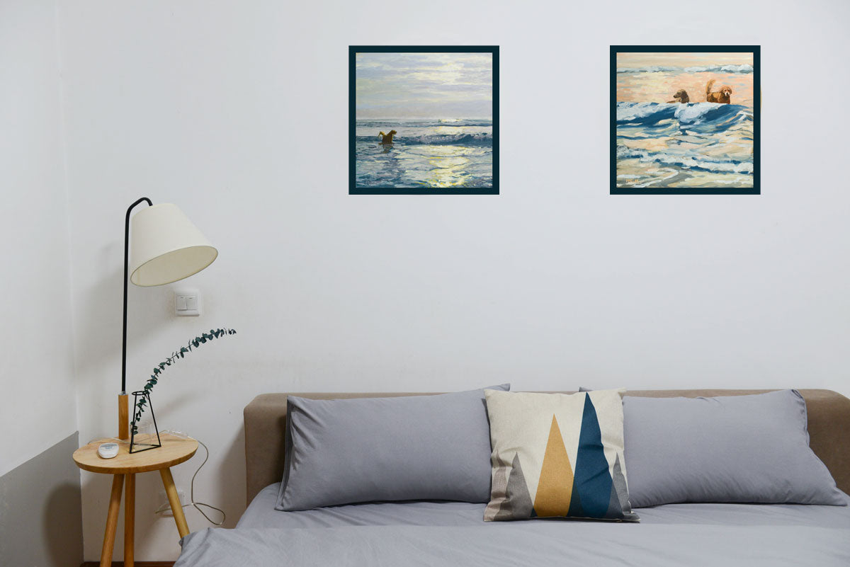 Two framed paintings of dogs on a beach by Hannah Phelps shown hung in a bedroom